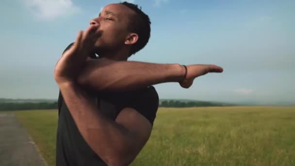 Sportlicher afrikanischer Mann streckt vor dem Laufen im Freien die Arme aus — Stockvideo