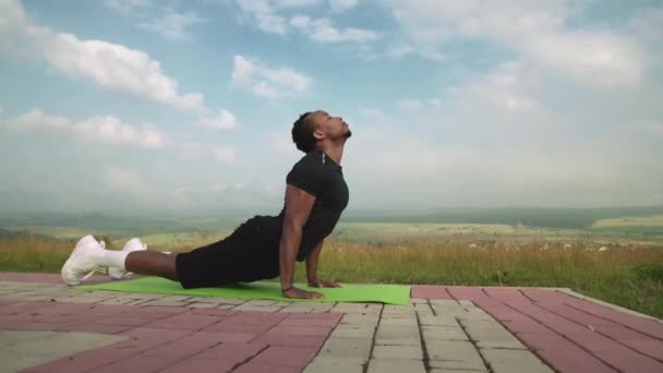 Afro americano fitness homem que se estende para trás ioga pose no tapete — Vídeo de Stock