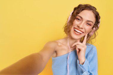 Neşeli model kulaklıkla müzik dinliyor, gülümsüyor..