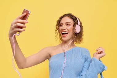 Selfie çeken, müzik dinleyen, poz veren bir kız..