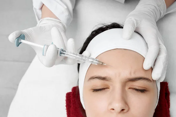 Médico profesional pinchando colágeno en la frente — Foto de Stock