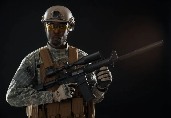 Soldado seriamente americano de uniforme segurando arma moderna . — Fotografia de Stock