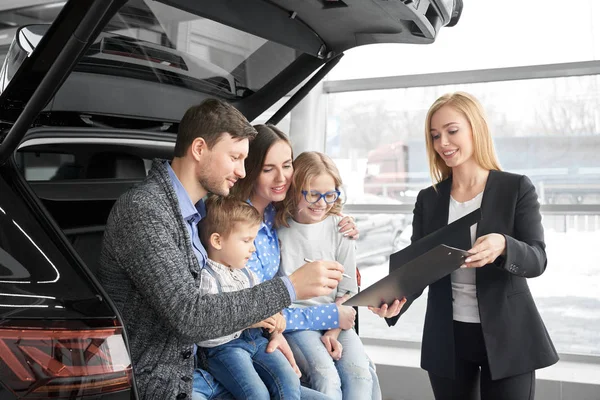 Счастливая семья покупает новый комфортабельный черный автомобиль в автосалоне — стоковое фото