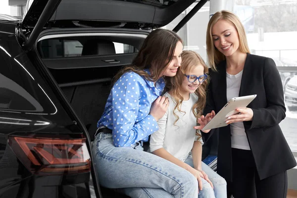 Car dealer consulting and helping family in choosing auto — Stockfoto