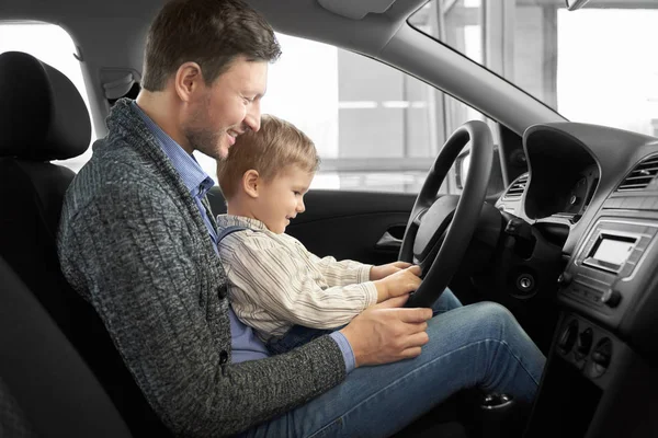 Pai bonito com filho sentado no assento do motorista em carro novo — Fotografia de Stock