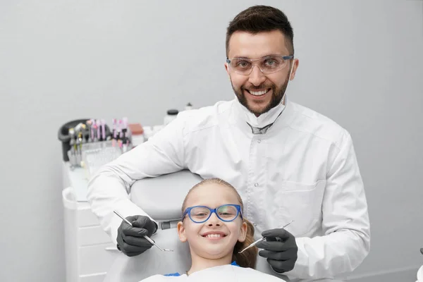 Knappe mannelijke tandarts glimlachen terwijl het genezen van tanden — Stockfoto
