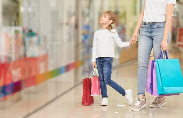 Zabawna dziewczyna trzyma rękę matki w centrum handlowym torba — Zdjęcie stockowe
