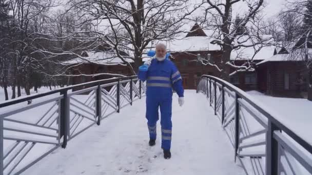 Old cleaner walking with shovel on shoulder. — Stock Video