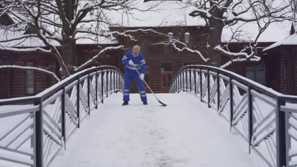 Senior takarító eltávolítása hó seprűvel. — Stock videók