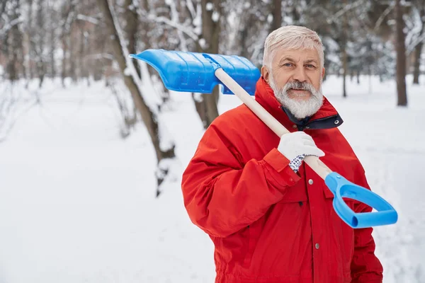 Férfi nézi a kamerát, miközben takarítás park hó — Stock Fotó