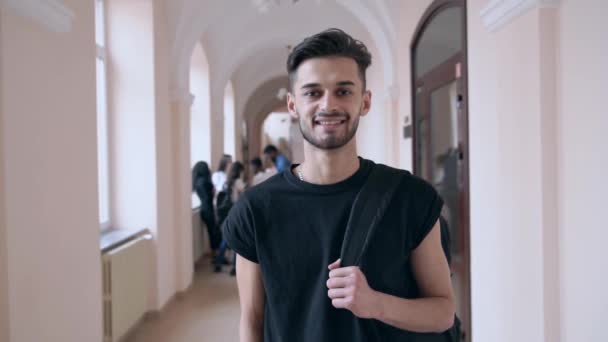 Vrolijke student glimlachen, poseren in de universiteitshal. — Stockvideo