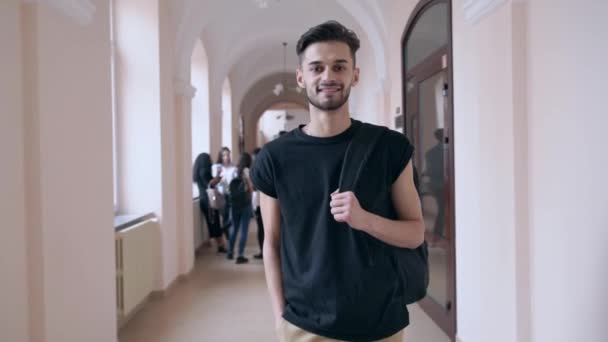 Jovem bonito com mochila posando no salão da universidade . — Vídeo de Stock