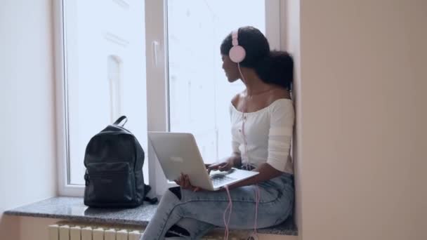 Pretty student girl sitting at window sill with laptop. — Stock Video