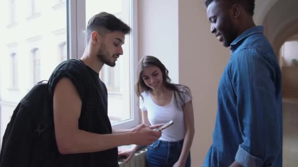 Étudiants tenant gadget, parler dans la salle universitaire .