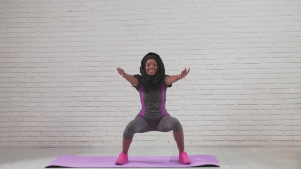 African woman doing squats on mat. — Stock Video