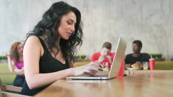 Usmívající se žena pomocí přenosného počítače v kavárně. — Stock video