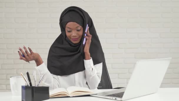 African woman talking on phone while studying. — Stock Video