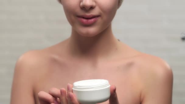 Femme en serviette mettre de la crème sur le visage . — Video