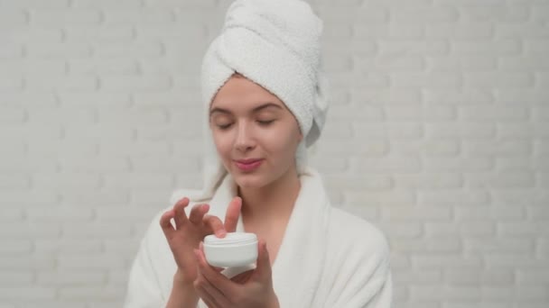 Mujer en toalla poniendo crema en la cara . — Vídeos de Stock
