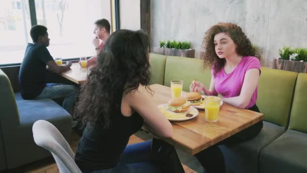 Zwei Freundinnen essen Fast Food und reden. — Stockvideo