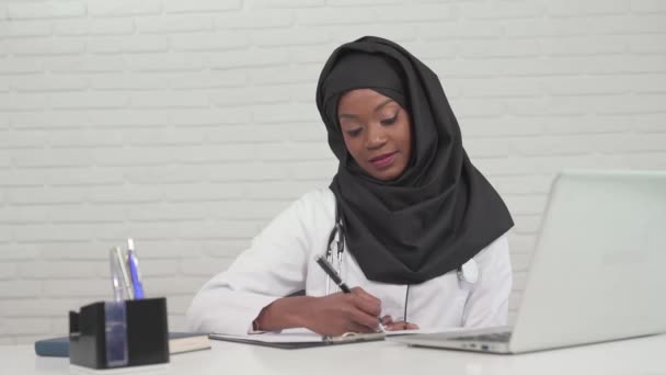 Female doctor writing notes in office. — Stock Video