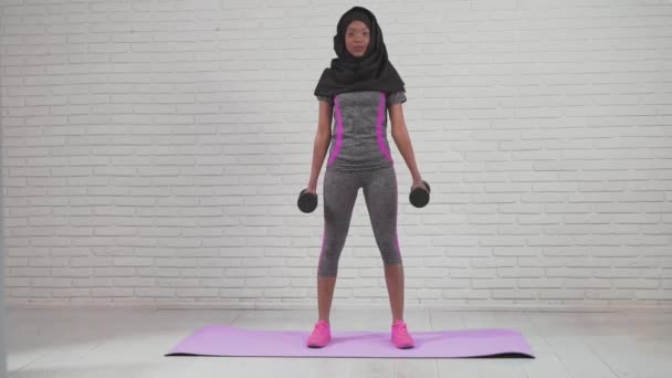 Afrikansk kvinna tränar armar med hantlar. — Stockvideo