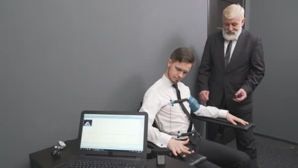 Aged man attaching sensors on fingers and body to young guy — Stock Video