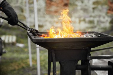 Demirci yanan kömürde metal parçasını ısıtıyor..