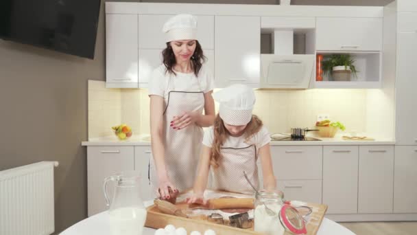 Madre en delantal de cocina y sombrero enseñando a la hija a cocinar — Vídeos de Stock