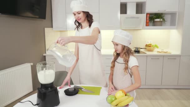 Feliz madre y bonita hija haciendo milkshake en mixer — Vídeos de Stock