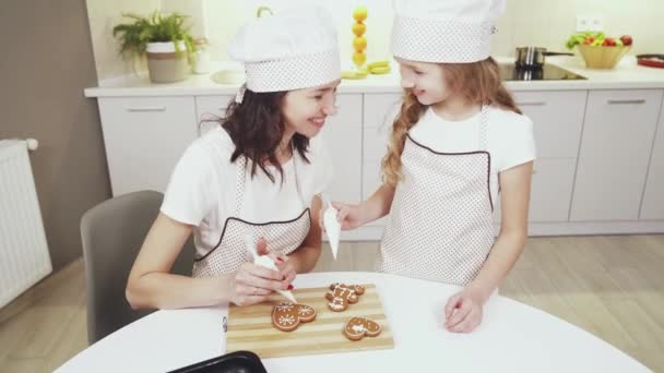 Очаровательная мать и милая дочь, глазирующие имбирное печенье — стоковое видео