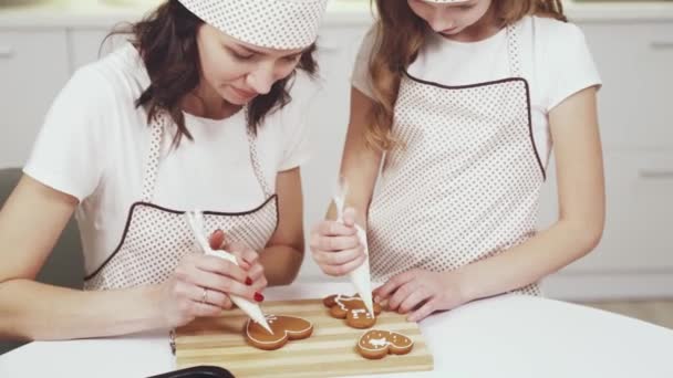 Чарівна жінка і маленька дівчинка прикрашають імбирне печиво — стокове відео