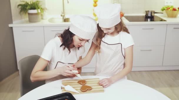 Beautiful mother teaching pretty child how to cook biscuits — Stock Video