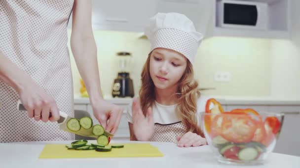 Ładne dziecko patrząc jak jej matka gotuje świeżą sałatkę — Wideo stockowe