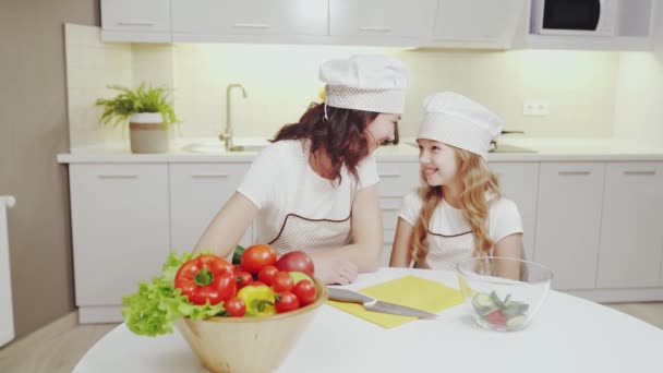 Joven madre y su hija preparando la comida en la cocina — Vídeo de stock