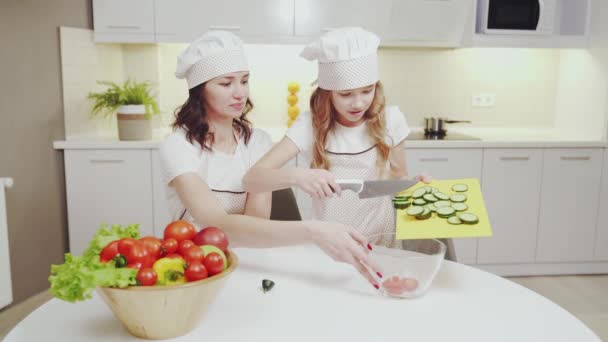 Feliz madre e hija cocinando ensalada de verduras juntos — Vídeo de stock