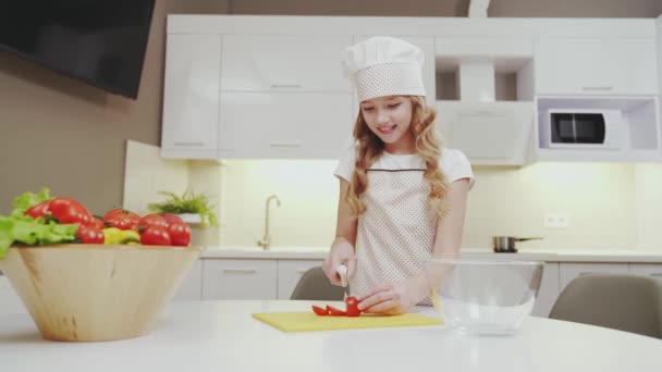 Linda chica en delantal de cocina y sombrero de corte de tomate para ensalada — Vídeos de Stock