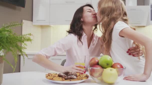 Niña y encantadora mujer sentada a la mesa en la cocina — Vídeo de stock