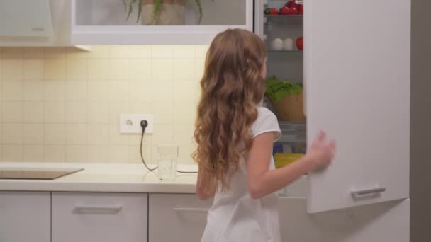 Cute little girl opening refregirator to take orange juice — Stock Video