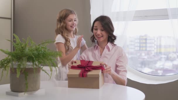 Chica joven besando y abrazando a su mamá mientras que da caja de regalo — Vídeo de stock