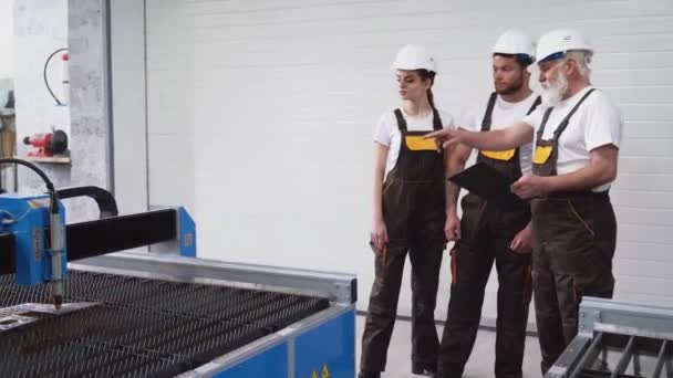 Tres ingenieros inspeccionan el cortador de plasma de trabajo . — Vídeo de stock