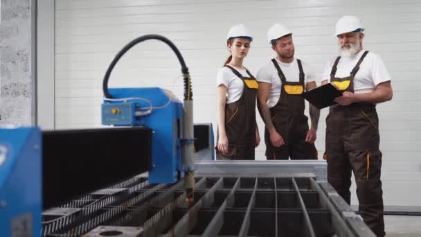 Drei Ingenieure inspizieren Plasmaschneidmaschine. — Stockvideo