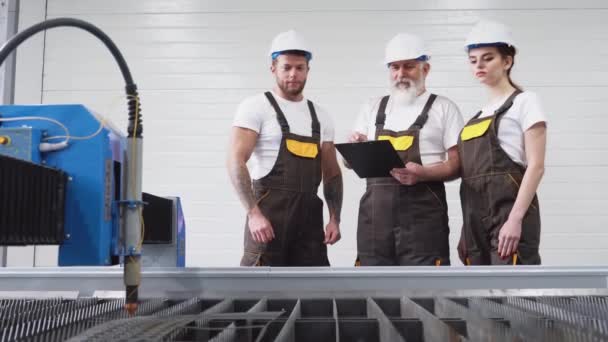 Drei Ingenieure inspizieren Plasmaschneidmaschine. — Stockvideo