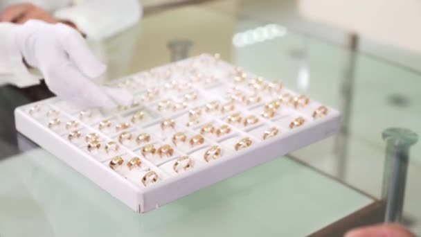 Zamknij białe pudełko pełne złotych pierścionków w sklepie jubilerskim — Wideo stockowe