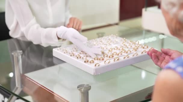 Female clerk in white gloves showing variety of golden rings — 비디오