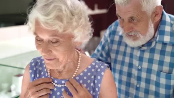 Vrolijk oud getrouwd stel kopen parel ketting in de winkel — Stockvideo