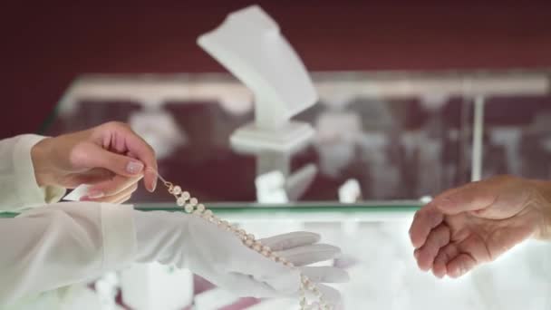 Gros plan du collier de perles dans les mains de la femme en gants blancs — Video