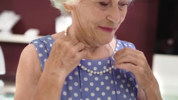 Portret van volwassen vrouw probeert op parel ketting in de winkel — Stockvideo