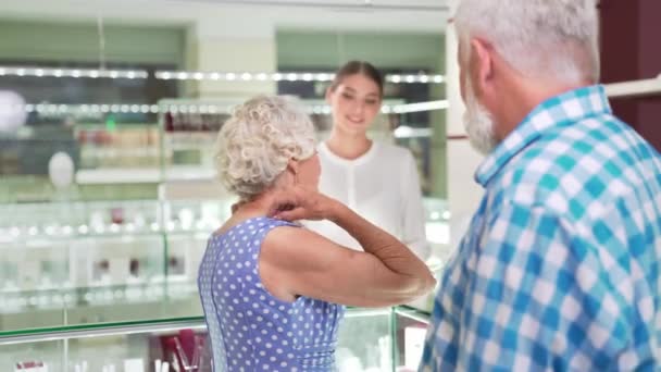 Okouzlující starší žena se snaží na perlový náhrdelník v obchodě — Stock video
