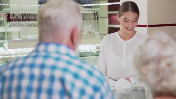 Schöne Expertin hilft alten Paaren bei der Schmuckauswahl — Stockvideo